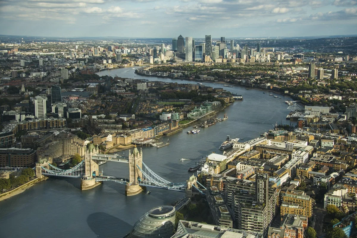 Aerial view of the Thames winding past Tower Bridge towards the Canary Wharf towers on an autumn afternoon